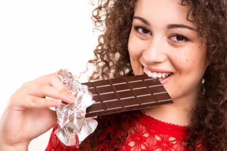Beautiful young woman eating a chocolate barの写真素材