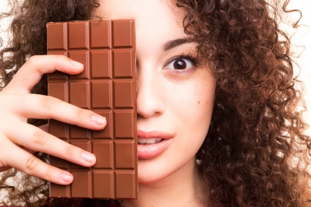Beautiful young woman eating a chocolate barの写真素材