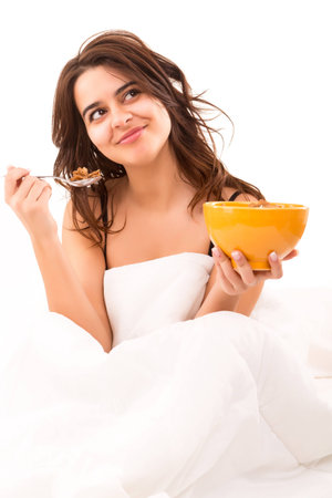 Young beautiful woman having breakfast in bedの写真素材