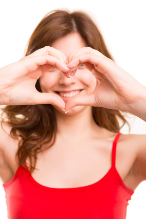 Beautiful woman making a heart shape with her hands, isolated over white backgroundの写真素材