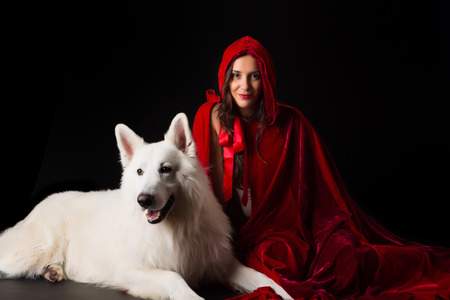 Woman wearing a red hood posing in studio with her dogの写真素材