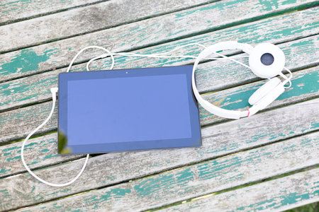 Tablet computer with headphones against wooden backgroundの写真素材