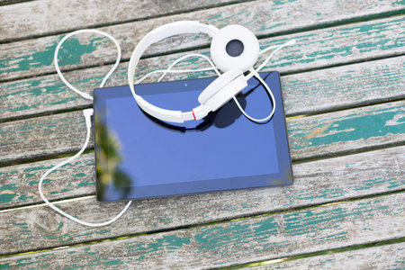 Tablet computer with headphones against wooden backgroundの写真素材