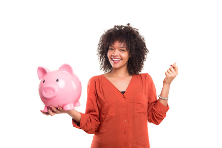 African woman putting some money into a piggy bankの写真素材