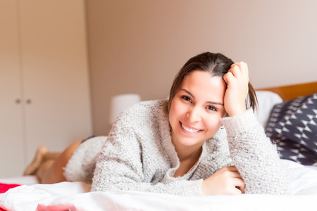 Young woman relaxing with her computer in bedの写真素材