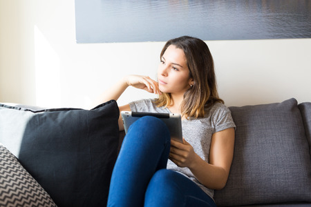 Beautiful young woman relaxing at the living roomの写真素材