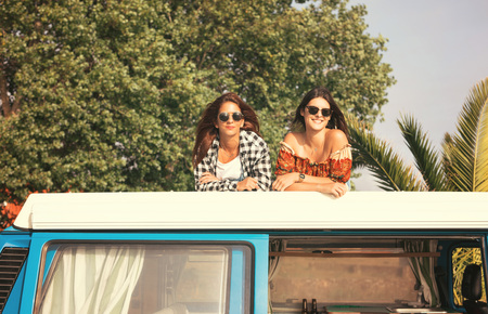 Summer holidays, road trip, vacation, travel and people concept - smiling young hippie women in carの写真素材