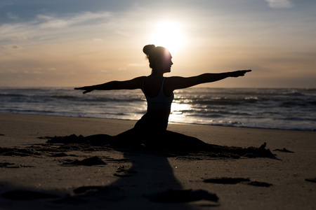 Sporty young woman doing yoga practice at the beach - concept of healthy life and natural balance between body and mental developmentの写真素材