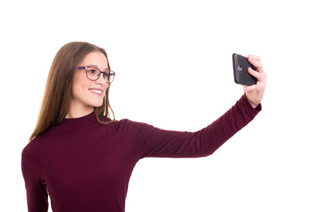 Happy young woman taking self portrait photography through smart phone over white background.の写真素材