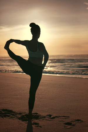 Sporty young woman doing yoga practice at the beach - concept of healthy life and natural balance between body and mental developmentの写真素材