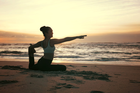 Sporty young woman doing yoga practice at the beach - concept of healthy life and natural balance between body and mental developmentの写真素材