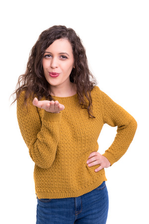 Beautiful young woman blowing you a kiss, isolated over whiteの写真素材