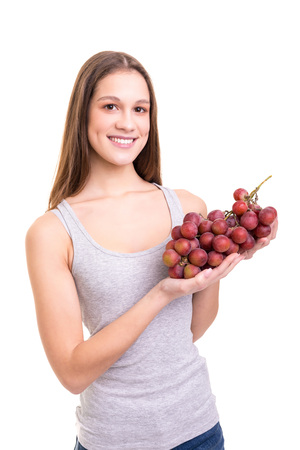 Young woman holding a bunch of fresh grapes, isolated over white backgroundの写真素材