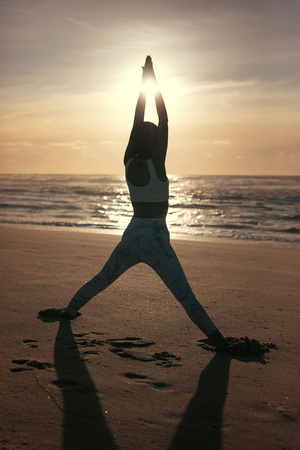 Sporty young woman doing yoga practice at the beach - concept of healthy life and natural balance between body and mental developmentの写真素材