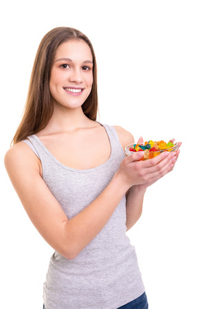 Young woman holding a bowl of jelly gummy bears, isolated over white backgroundの写真素材