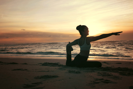 Sporty young woman doing yoga practice at the beach - concept of healthy life and natural balance between body and mental developmentの写真素材