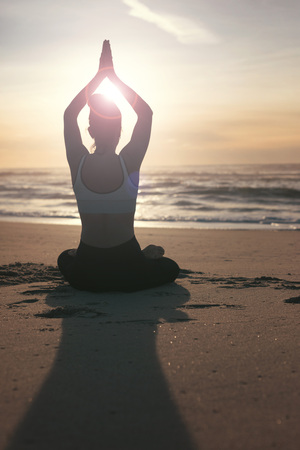 Sporty young woman doing yoga practice at the beach - concept of healthy life and natural balance between body and mental developmentの写真素材
