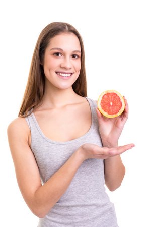 Young woman holding a fresh grapefruit, isolated over white backgroundの写真素材