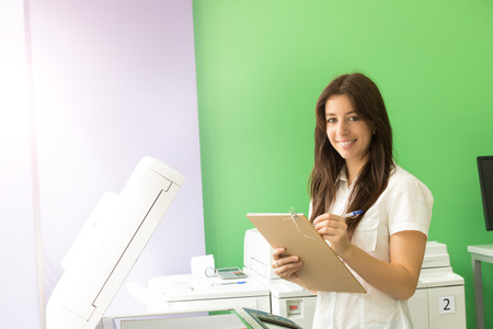 A young student at a copy center taking some copies for her final examsの写真素材