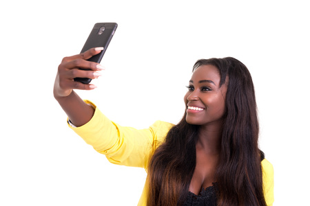 Happy young woman taking self portrait photography through smart phone over whiteの写真素材