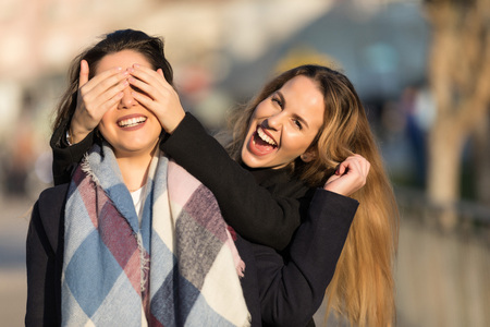 Young pretty girls best friends smiling and having fun, walking at the city. Shopping. Wearing stylish outerwear. Bright make up. Positive emotions. Outdoors lifestyle fashion close up portraitの写真素材