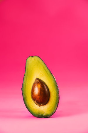 Tropical summer background. Green avocado on a pink background. Food concept