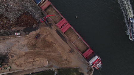 Aerial top down view of a ship and crane loading ground into a large freight ship. Excavator