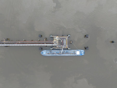 top down view on a inland shipping bulk carrier docked moored at a loading and unloading terminal...