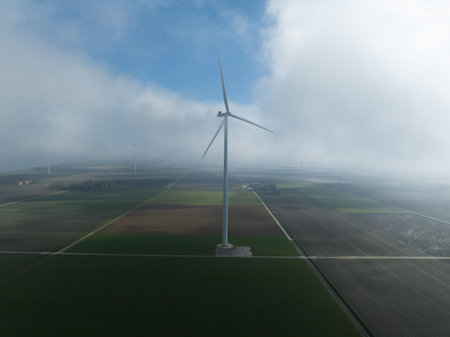 Wind turbine surrounded by low hanging clouds, aerial drone view, renewable energy.の写真素材