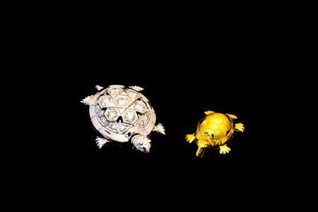 Silver with diamond turtle and golden turtle on black backgroundの写真素材