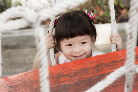 smiling girl hiding behind jungle gymの写真素材