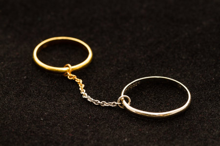gold and silver rings connected by chain on black background