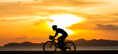 man biking his bicycle on the beach with sunset view の写真素材