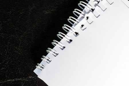 part of white spiral notebook on black leather skin
