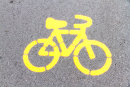 yellow neon bicycle symbol on roadの写真素材