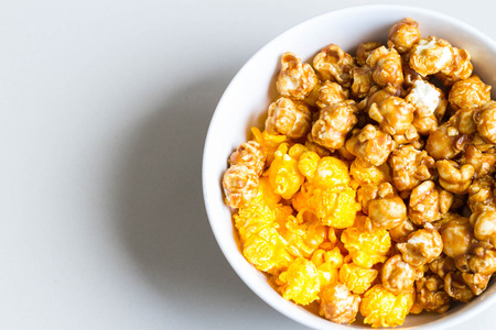 half cheese and half caramel popcorn in white bowl on rightの写真素材