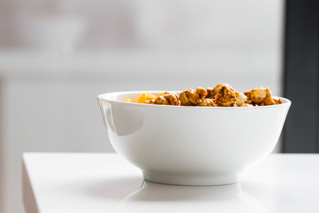 cheese and caramel popcorn in white bowl, side shotの写真素材