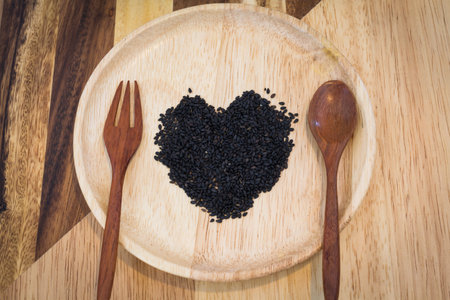 heart shape black sesame on wooden plateの写真素材