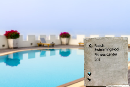 cement direction sign with swimming pool in backgroundの写真素材