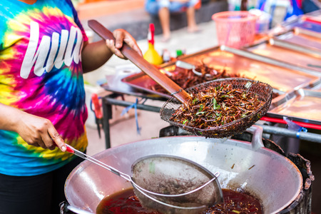 woman is frying grasshoppers at marketの写真素材