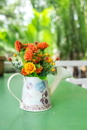 colorful fabric flowers in watering pot decorated on tableの写真素材