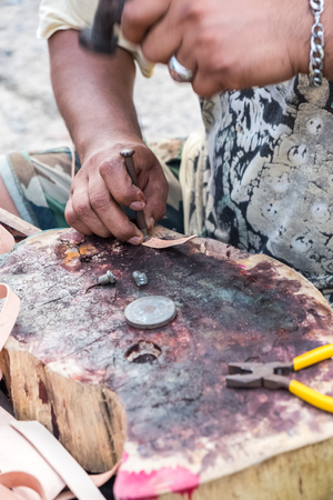 man hammering english character on leather for handmade braceletの写真素材