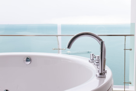 closeup part of bathtub and faucet with sea viewの写真素材