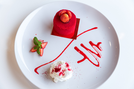 red velvet cake with fresh strawberry on top decorated with whipping cream and strawberry syrupの写真素材