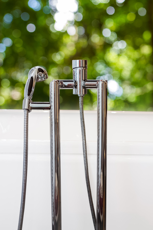 closeup bathtub faucet with green bokeh backgroundの写真素材