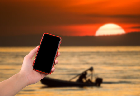 hand holding smartphone on sunset backgroundの写真素材