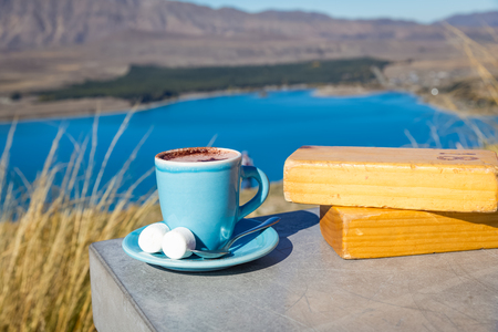 cup of hot chocolate with marshmallow on cement table with Lake Tekapo viewの写真素材