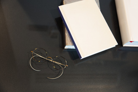 blank cover books and old style glasses on table with light in vintage toneの写真素材