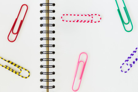 colorful paper clips spread on blank notebookの写真素材