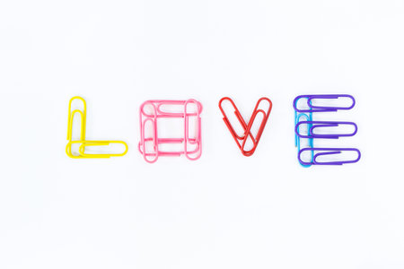 colorful paper clips arranged in word LOVE on white background